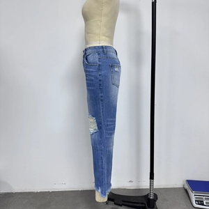 Detail van distressed knie gaten en rafelige zoom op de blauwe wijde denim jeans