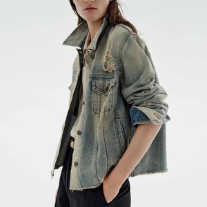 Detail of vintage washed denim jacket with distressed hem and retro copper buttons