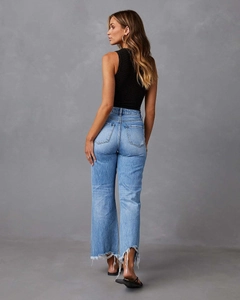 Detail van een lichtblauwe jeans met wijde pijpen, gerafelde zoom en denim textuur