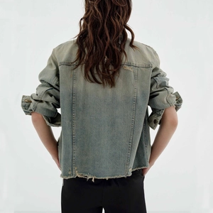 Detail view of vintage blue denim jacket with distressed hem and frayed back seams