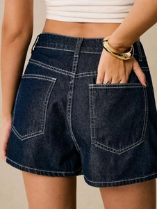 Detail of high-waisted dark blue denim shorts with white contrast stitching and back pockets