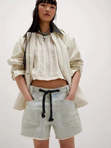 Women's casual street style outfit with beige utility jacket and denim shorts