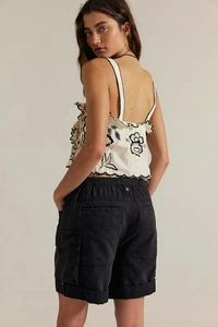 Détail du haut blanc brodé de fleurs et du short cargo noir porté par un mannequin