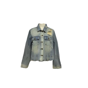 Detail of distressed light blue denim jacket featuring vintage frayed collar and chest pockets