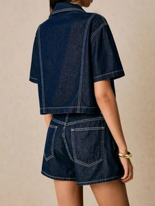 Detail view of high-waisted denim shorts with white contrast stitching and rear pockets