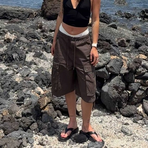Detailed view of dark brown cargo shorts with large flap pockets and drawstring waist