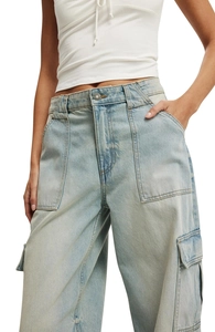 Detail of high-waist light blue cargo jeans with large pockets and metal button closure