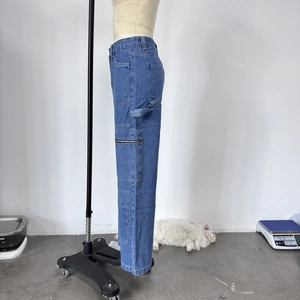 Detail view of denim cargo pants with tool loop and metal zipper pocket design