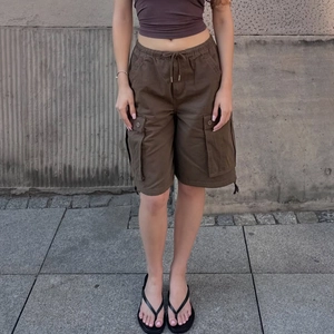 Detail of dark coffee cargo shorts featuring elastic drawstring waist and large side pockets