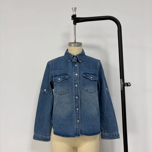 Detail of blue denim jacket showing flap chest pockets and metal button closure