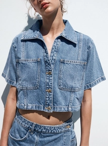 Detailed close-up of light wash denim shirt set featuring metal buttons and utility pockets