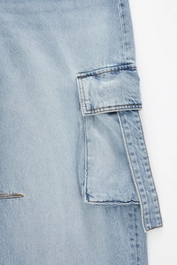 Gros plan d'une poche cargo sur jean en denim bleu clair montrant coutures et texture