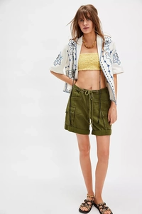 Détail d'une chemise blanche brodée bleue avec crop top jaune et short cargo vert