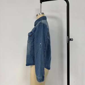 Detail of blue denim shirt featuring a classic collar, chest pocket, and washed fabric texture