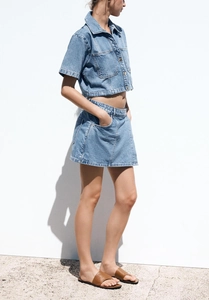 Side view of light blue denim shirt and mini skirt set with dual chest pockets