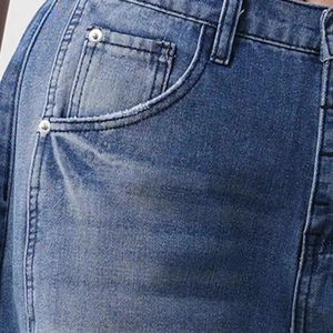 Detail of retro washed blue denim jeans showing front pocket and metal rivet reinforcement