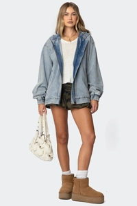 Full view of oversized light blue hooded denim jacket with camouflage shorts and snow boots