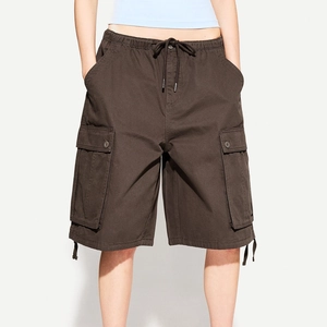 Detail of dark brown cargo shorts showing elastic drawstring waist and large utility pockets