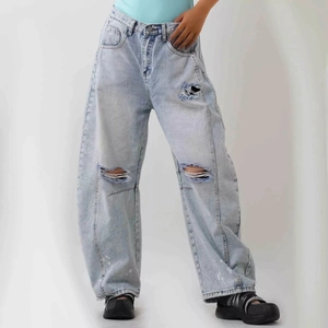 Detailed view of wide-leg light blue jeans featuring heavy wash and ripped knee distressing