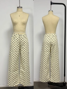 Close-up of high-waisted wide-leg denim pants featuring a retro black polka dot pattern