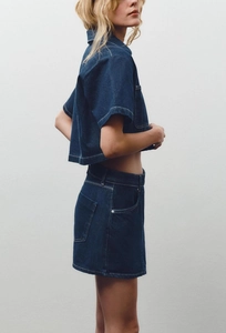 Detail of dark blue denim set with white contrast stitching on the crop shirt and skirt