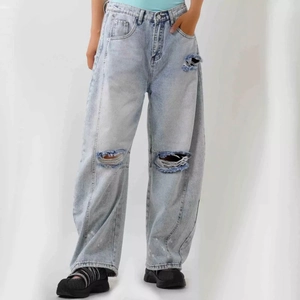 Close-up of distressed light blue wide-leg denim jeans featuring ripped knee details