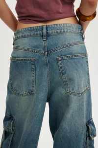 Gros plan sur la texture du jean cargo bleu clair et les poches latérales