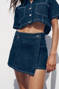 Detail of dark blue denim set with white contrast stitching and metallic buttons