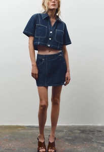 Detail of dark blue denim two-piece set with silver buttons and contrast stitching details