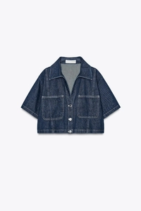 Detail of dark blue cropped denim jacket with contrast stitching and metal buttons