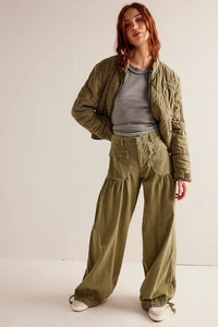 Dettaglio dei pantaloni cargo larghi verde militare con coulisse e giacca trapuntata