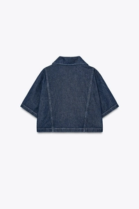 Back view of dark blue denim shirt with white contrast stitching and loose cropped fit