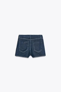 Detail view of denim shorts featuring back pockets with white contrast stitching