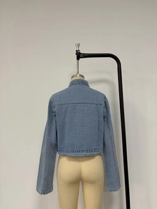 Détail de la veste courte en jean bleu clair avec col rabattu et coutures apparentes