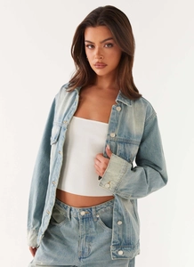 Detail of light blue washed denim jacket with silver metal buttons and loose fit silhouette