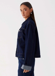 Détails d'une veste en jean bleu foncé avec boutons métalliques et col classique