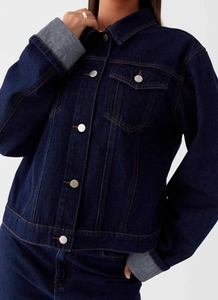 Détail d'une veste en jean bleu foncé avec coutures contrastées et boutons argentés