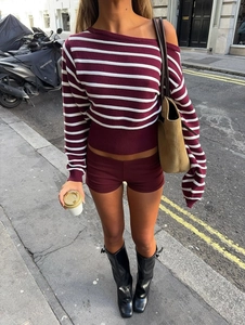 Outdoor street shot of a woman in striped off-shoulder knit top and burgundy shorts