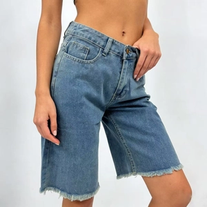 Detail of high-waisted mid-blue denim Bermuda shorts with raw hem and vintage wash finish
