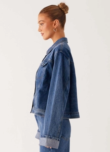 Détail d'une veste en jean bleue montrant la texture du tissu et la poche poitrine