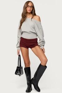 Detailed view of women's slim burgundy shorts paired with black boots and a grey knit top