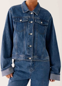 Détail de la veste en jean bleu foncé avec boutons métalliques et poches poitrine
