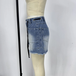 Close-up of washed blue denim skirt with distressed hem and black drawstring detail