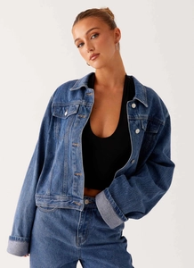 Détail d'une veste en jean bleu moyen oversize avec boutons argentés et épaules tombantes