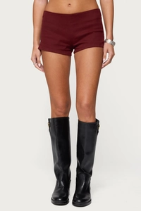 Detail of slim fit burgundy denim shorts paired with black knee-high leather boots