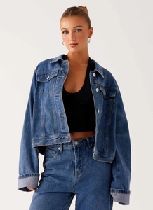 Détail d'un ensemble veste en jean bleu foncé avec col à revers et boutons métalliques
