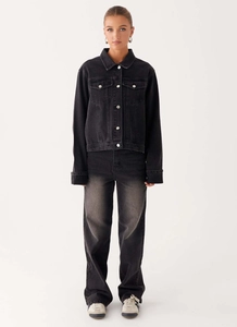 Détail d'une veste en jean noir délavé avec boutons métalliques et poches de poitrine