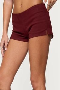 Detail view of burgundy slim fit denim shorts featuring side V-cut slits and high waist