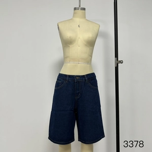 Detail of waist area on dark blue denim shorts featuring belt loops and metal button