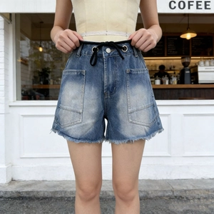 Detail of high-waist denim shorts featuring retro washing and decorative black drawstrings